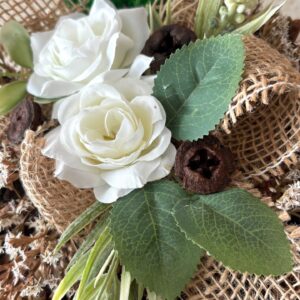 Sírdísz lakkozott toboz koszorú alapon, hófehér rózsákkal, zöldekkel, juta szalaggal, sóvirággal díszítve